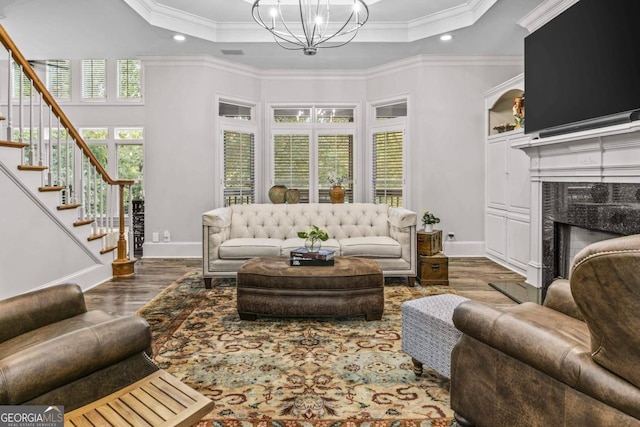 living room with a high end fireplace, dark hardwood / wood-style floors, a tray ceiling, and ornamental molding