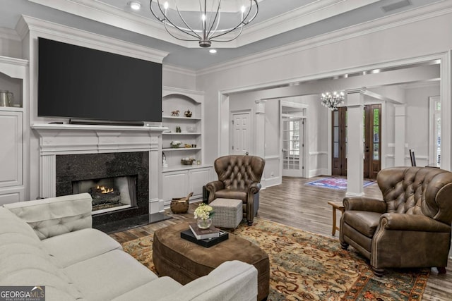 living room featuring built in features, a high end fireplace, a notable chandelier, crown molding, and dark hardwood / wood-style floors