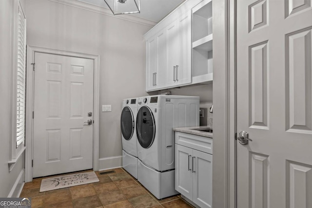 laundry room featuring separate washer and dryer, crown molding, and cabinets