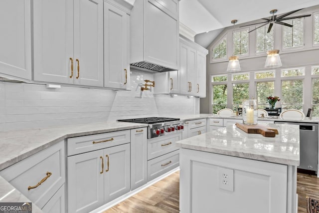 kitchen with ceiling fan, light stone countertops, decorative backsplash, custom range hood, and light wood-type flooring