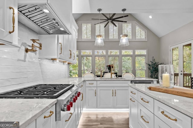 kitchen with french doors, premium range hood, light stone counters, white cabinets, and hanging light fixtures