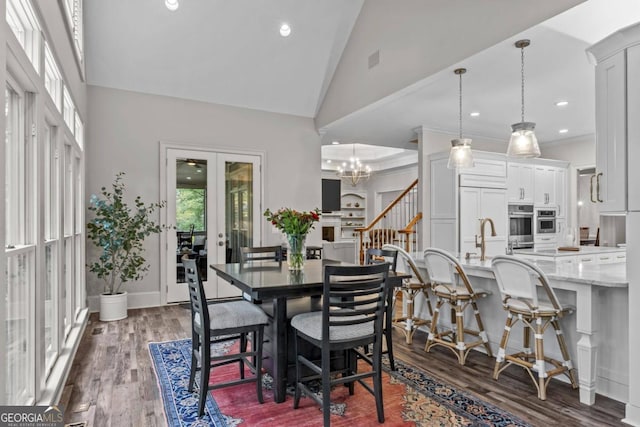 dining area featuring french doors, high vaulted ceiling, dark wood-type flooring, and a notable chandelier