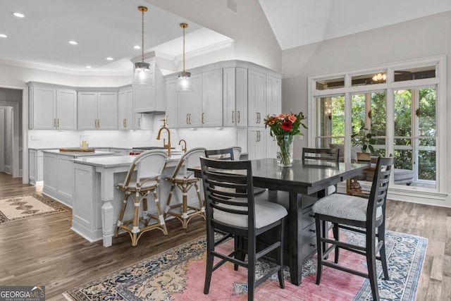 dining room with lofted ceiling, sink, crown molding, and dark hardwood / wood-style floors