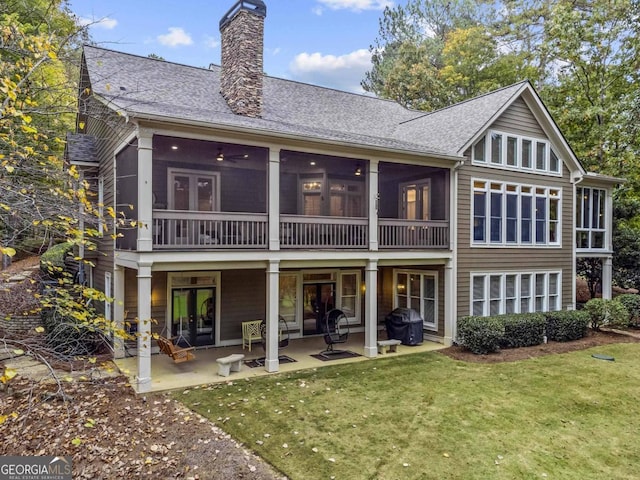 rear view of property featuring a yard, a patio, and a sunroom