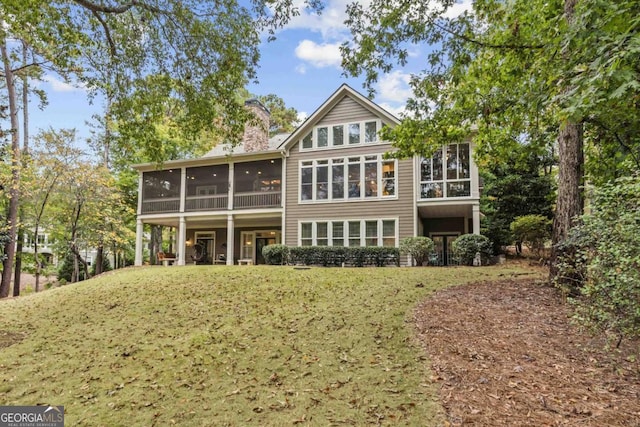 back of house featuring a yard and a sunroom