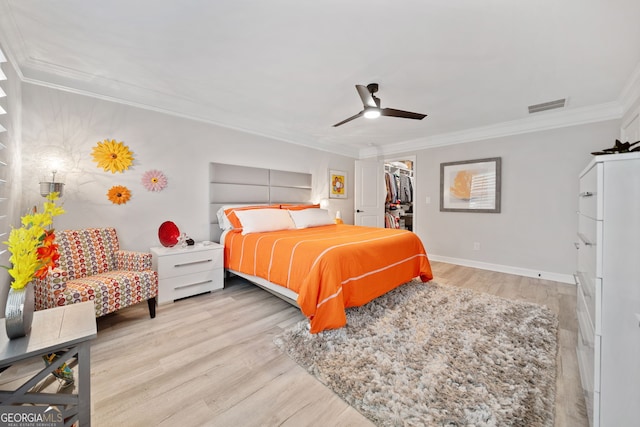 bedroom featuring crown molding, ceiling fan, a spacious closet, a closet, and light wood-type flooring