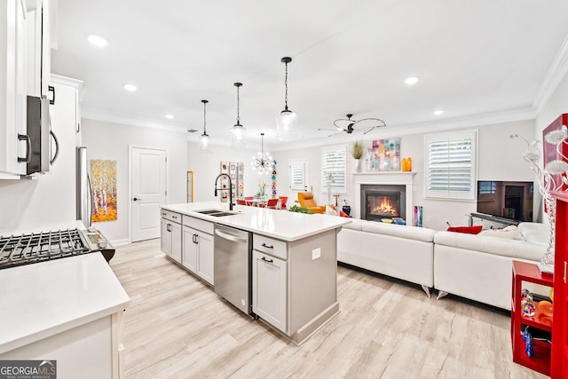 kitchen with white cabinetry, sink, hanging light fixtures, stainless steel appliances, and a center island with sink