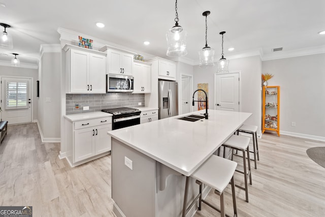 kitchen featuring a breakfast bar, sink, white cabinetry, appliances with stainless steel finishes, and a kitchen island with sink