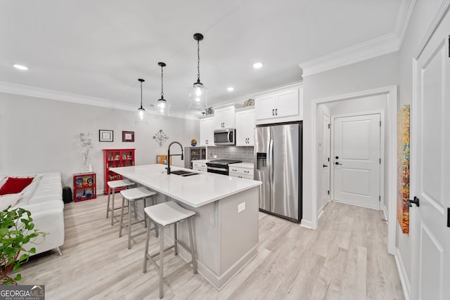 kitchen with white cabinetry, sink, a breakfast bar area, a kitchen island with sink, and stainless steel appliances