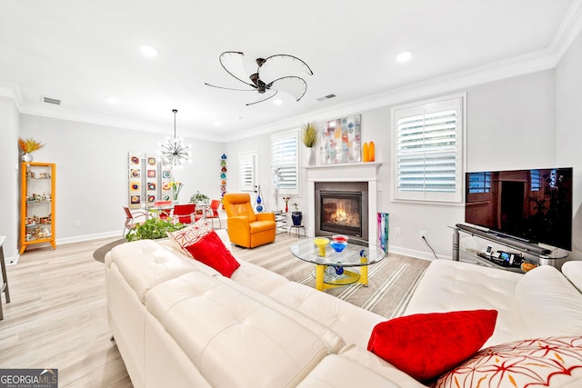 living room with ornamental molding, a chandelier, and light wood-type flooring