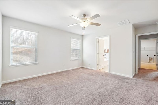 unfurnished bedroom featuring ceiling fan, light colored carpet, and ensuite bathroom