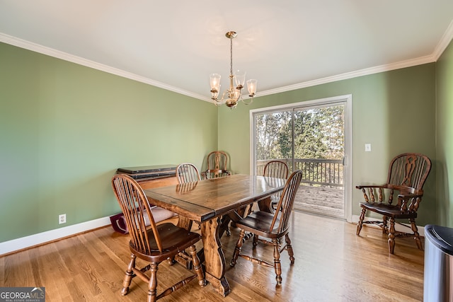 dining space with ornamental molding, light wood-type flooring, and an inviting chandelier