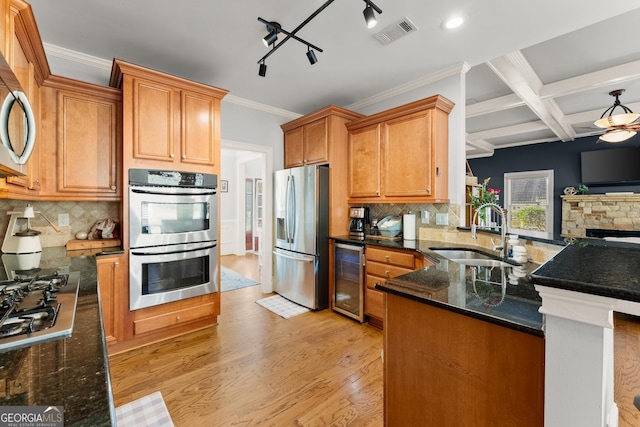 kitchen with kitchen peninsula, appliances with stainless steel finishes, sink, light hardwood / wood-style flooring, and wine cooler