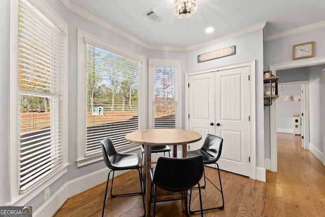 dining area featuring ornamental molding, light hardwood / wood-style flooring, and a healthy amount of sunlight