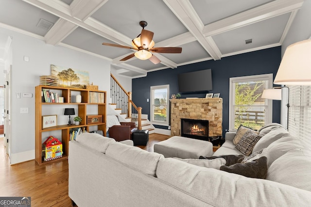 living room with ceiling fan, coffered ceiling, crown molding, a fireplace, and hardwood / wood-style flooring