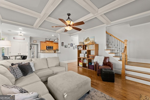 living room with ceiling fan, light wood-type flooring, crown molding, and coffered ceiling