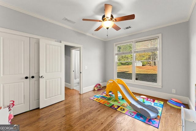 game room with wood-type flooring, ceiling fan, and crown molding