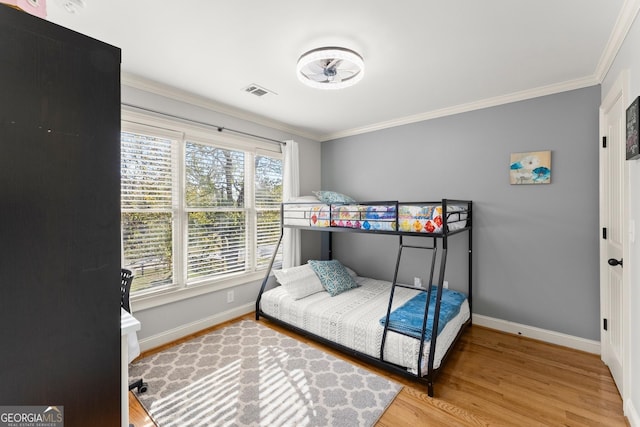 bedroom featuring wood-type flooring, multiple windows, and crown molding