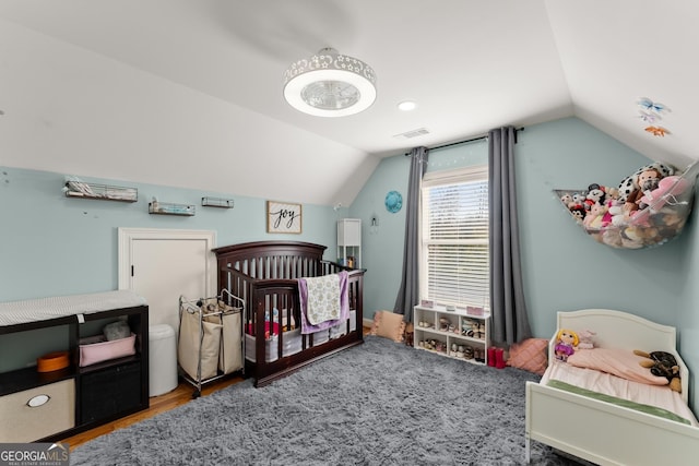 bedroom featuring hardwood / wood-style flooring, lofted ceiling, and a crib