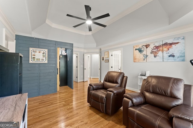 living room with a tray ceiling, ceiling fan, crown molding, and light hardwood / wood-style floors