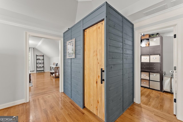 corridor featuring crown molding, light hardwood / wood-style flooring, and vaulted ceiling