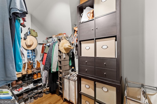 walk in closet with light hardwood / wood-style flooring and lofted ceiling