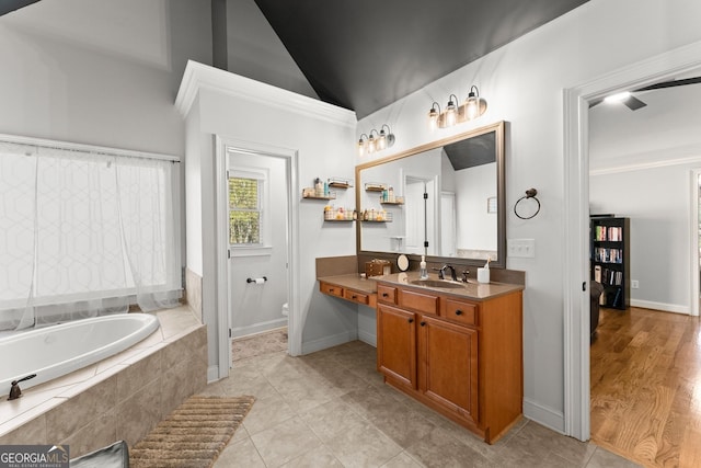 bathroom with tile patterned floors, tiled tub, lofted ceiling, vanity, and ornamental molding