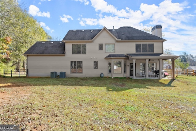 rear view of property featuring a lawn, ceiling fan, cooling unit, and a patio