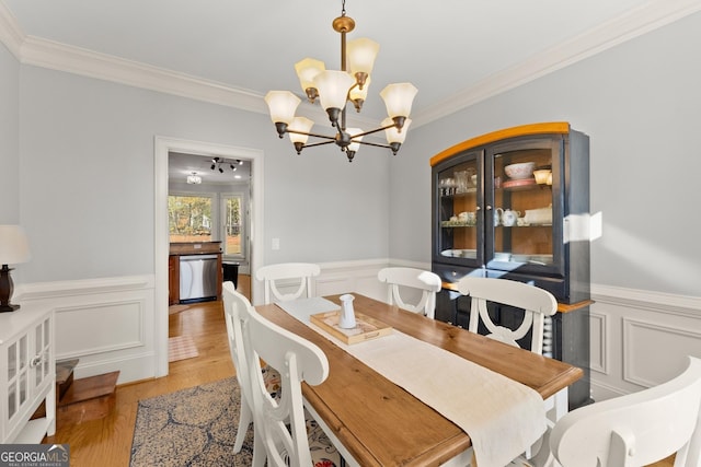 dining room with a notable chandelier, light wood-type flooring, and ornamental molding