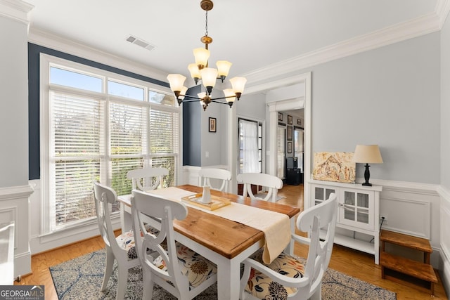 dining space with ornamental molding, light hardwood / wood-style floors, and a notable chandelier