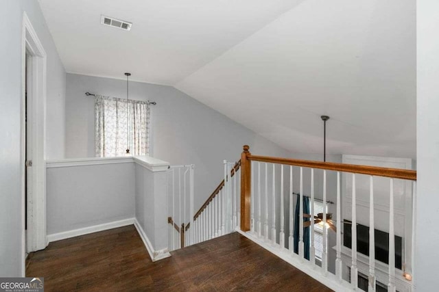 hall with lofted ceiling, dark wood-type flooring, and a notable chandelier