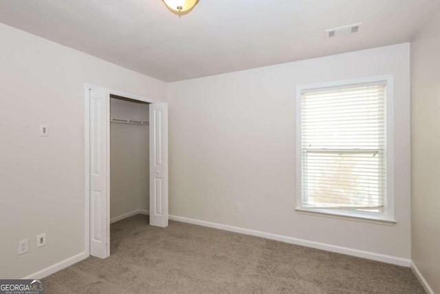 unfurnished bedroom featuring a closet and light carpet