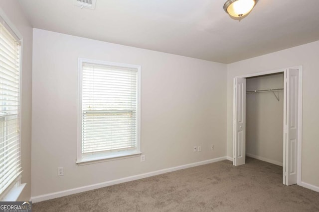 unfurnished bedroom with multiple windows, light carpet, and a closet