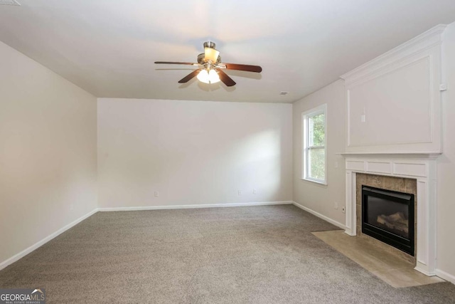 unfurnished living room with ceiling fan, a tiled fireplace, and carpet floors