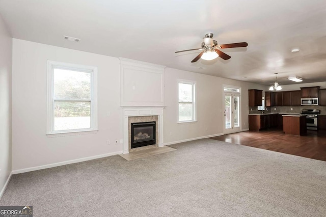 unfurnished living room with a tile fireplace, dark hardwood / wood-style flooring, ceiling fan, and sink