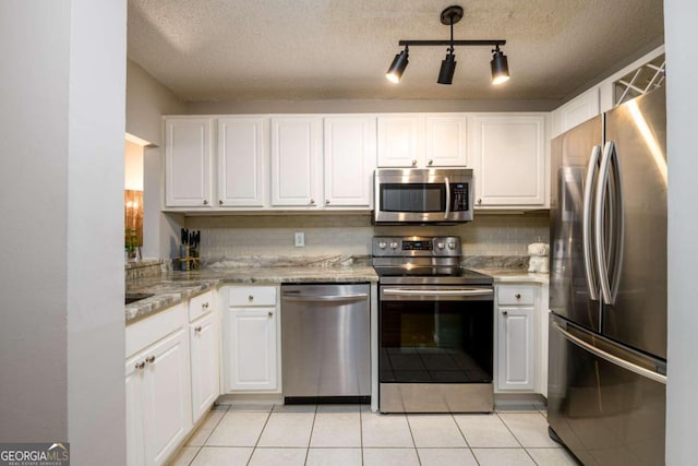 kitchen featuring white cabinetry, backsplash, a textured ceiling, light tile patterned floors, and appliances with stainless steel finishes