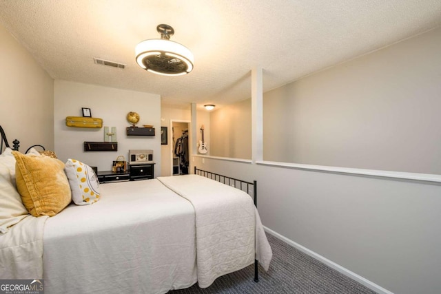 carpeted bedroom with a textured ceiling, a walk in closet, and a closet