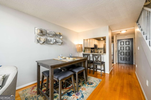 dining space featuring a textured ceiling and light hardwood / wood-style flooring