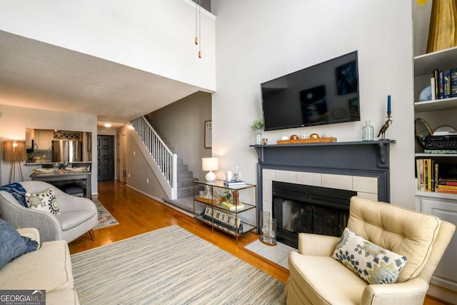 living room with a textured ceiling, light wood-type flooring, and a tiled fireplace