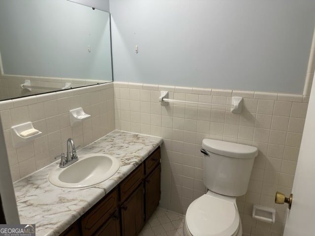 bathroom with tile patterned flooring, vanity, toilet, and tile walls