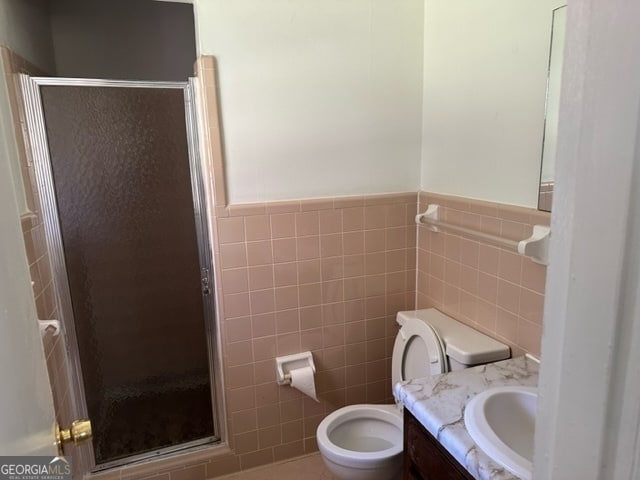 bathroom with walk in shower, vanity, toilet, and tile walls