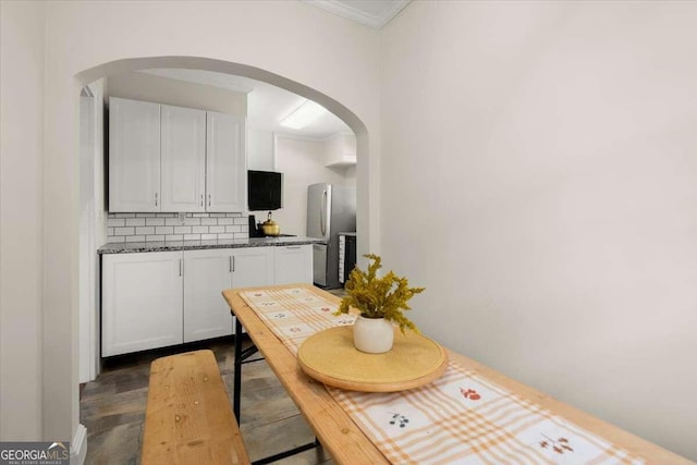 kitchen featuring stainless steel refrigerator, dark hardwood / wood-style flooring, crown molding, decorative backsplash, and white cabinets