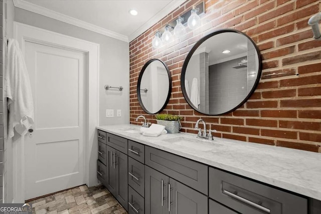 bathroom with crown molding, vanity, and brick wall