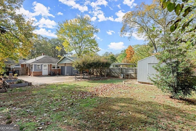 view of yard with a patio, a garage, and a storage shed