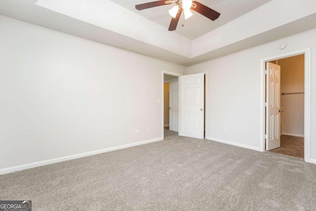 unfurnished bedroom with carpet, a spacious closet, and ceiling fan