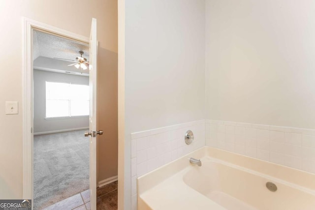 bathroom with tile patterned flooring, ceiling fan, a washtub, and a textured ceiling