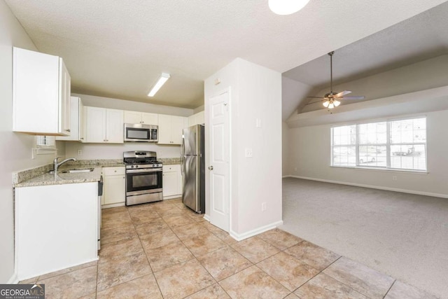 kitchen with white cabinetry, appliances with stainless steel finishes, lofted ceiling, and light colored carpet