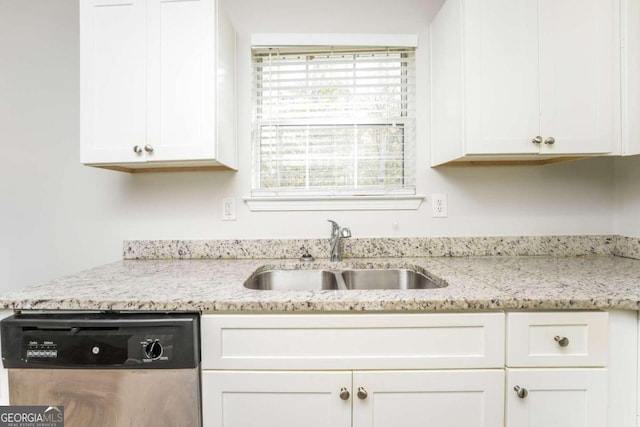 kitchen with light stone countertops, white cabinetry, stainless steel dishwasher, and sink