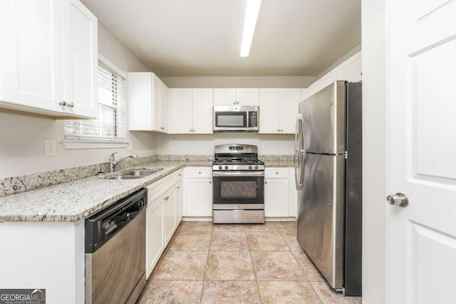 kitchen with appliances with stainless steel finishes, light stone counters, sink, white cabinets, and light tile patterned flooring