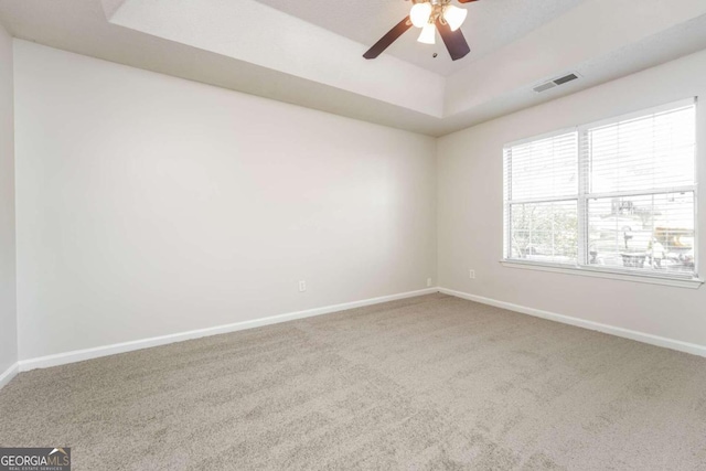 unfurnished room with carpet floors, a tray ceiling, and ceiling fan